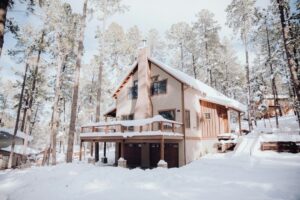 Snötäckt fjällstuga bland tallar med terrass och garage